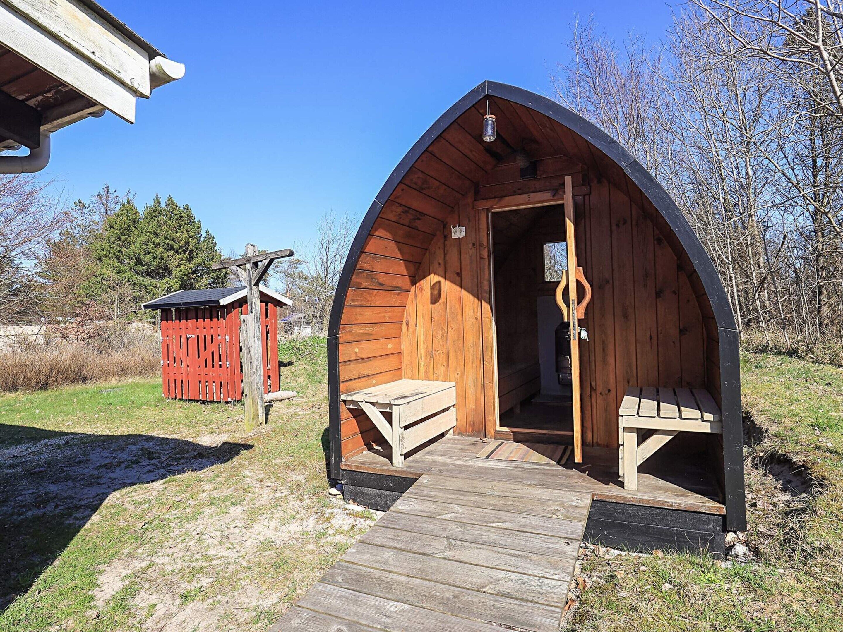Une cabane en bois avec un porche, un petit abri rouge et un ciel dégagé.