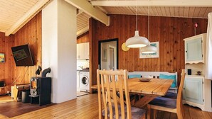 A wooden interior with a dining table, chairs, a bench, a stove, and a washing machine. - Pretty Holiday Home in Ålbæk near Sea (Aalbaek)