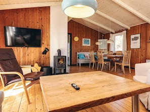 A cozy living room with a TV, wooden furniture, a fireplace, and a dining area.