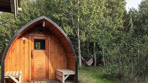 A wooden cabin with a porch, a bench, and a hammock. - Pretty Holiday Home in Ålbæk near Sea (Aalbaek)