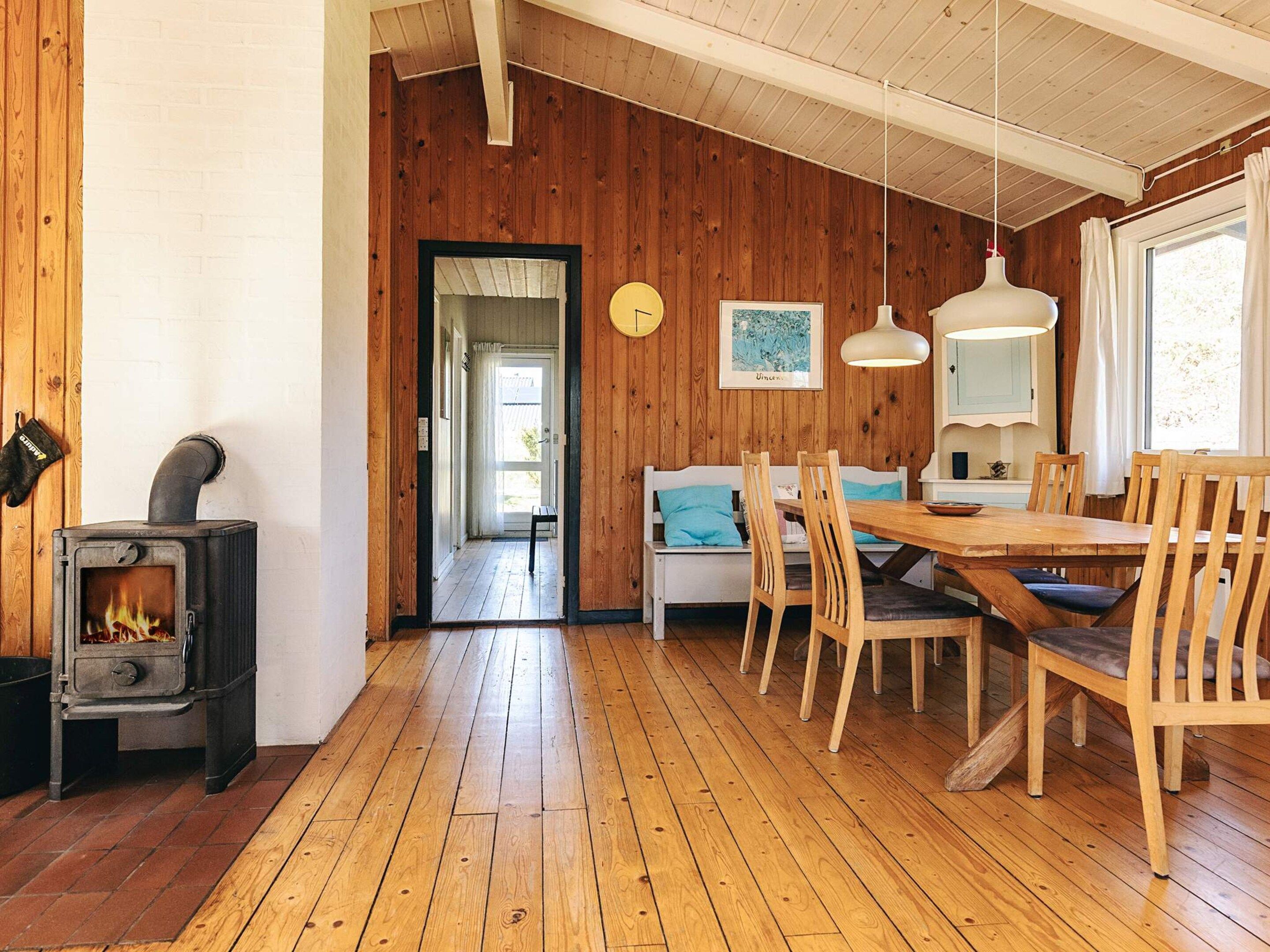A cozy room with a wood-burning stove, a dining table with chairs, and a bench.