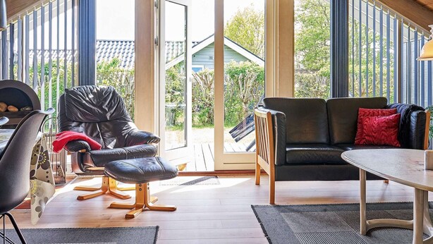 A cozy room with a wooden ceiling, a black leather chair, a black sofa, and a small table. - 6 Person Holiday Home in Hemmet (Hemmet)