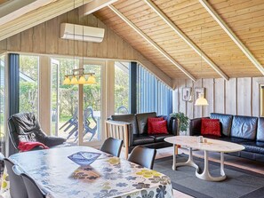 Relax in a spacious living area with a high ceiling and comfortable seating, featuring a sofa and chairs, a small table, and a floor lamp.