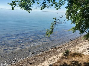 A clear lake with a rocky shoreline and trees framing the view. - 4 Star Holiday Home in Sjolund (Sjølund)