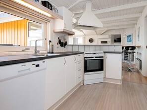 A modern kitchen with white cabinetry, a built-in oven, and a dishwasher. - 4 Star Holiday Home in Sjolund (Sjølund)