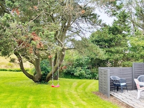 A garden with a swing, a wooden fence, and outdoor seating.