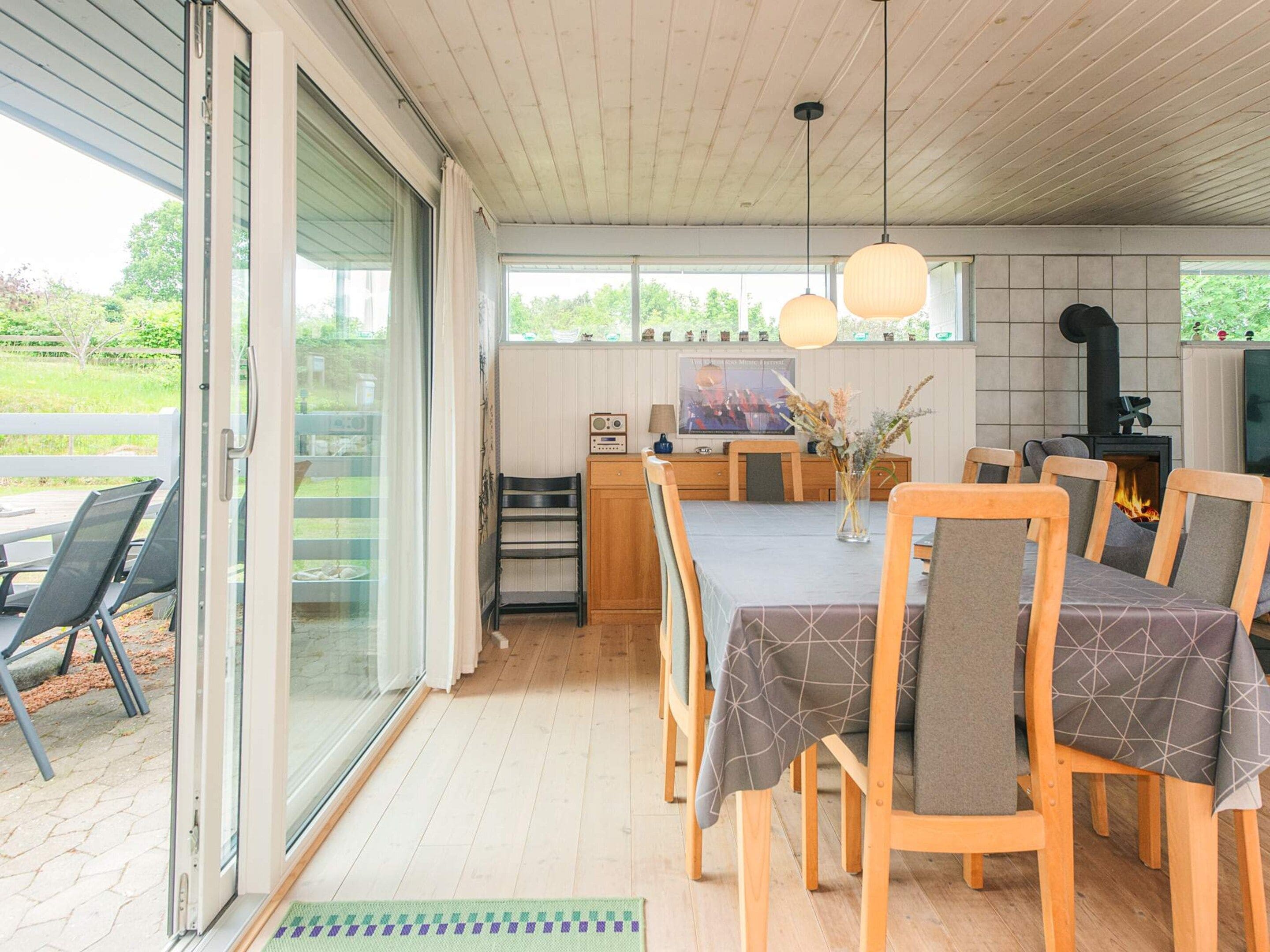 A modern kitchen with a dining area, a fireplace, and a large window.