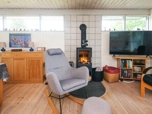 A cozy living room with a fireplace, a television, and a bookshelf.