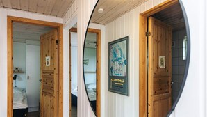 A room with wooden doors, a bed, a poster on the wall, and a mirror reflecting the room. - Quaint Holiday Home near Glesborg with Roofed Terrace (Glesborg)