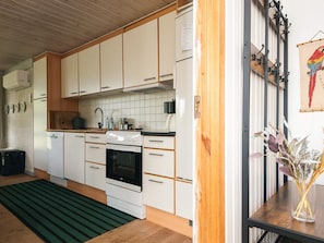 A modern kitchen with white cabinets, a stove, and a wooden floor.
