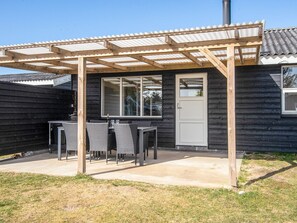 A wooden house with a covered patio, a door, and a window. - Peaceful Holiday Home in Jutland near Sea (Hvide Sande)