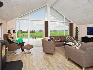 A spacious living room with a large glass door leading to a deck, furnished with sofas and a coffee table.