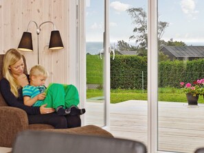 A room with a large window, a sofa, and two wall-mounted lamps.