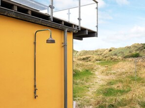 A yellow building with a metal structure on the roof, a metal pipe, and a grassy landscape in the background. - 5 Star Holiday Home in Brovst (Brovst)