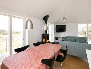 Een moderne woonruimte met een eethoek, een open haard, een bank en een televisie.
