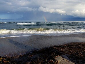 A beach with waves, pebbles, and a rainbow. - 5 Star Holiday Home in Brovst (Brovst)