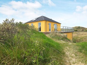 A yellow building with a balcony, surrounded by natural vegetation. - 5 Star Holiday Home in Brovst (Brovst)