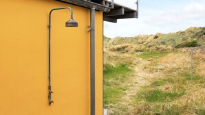 En gul bygning med en metalstruktur øverst, et metalrør og en lampe i metal.