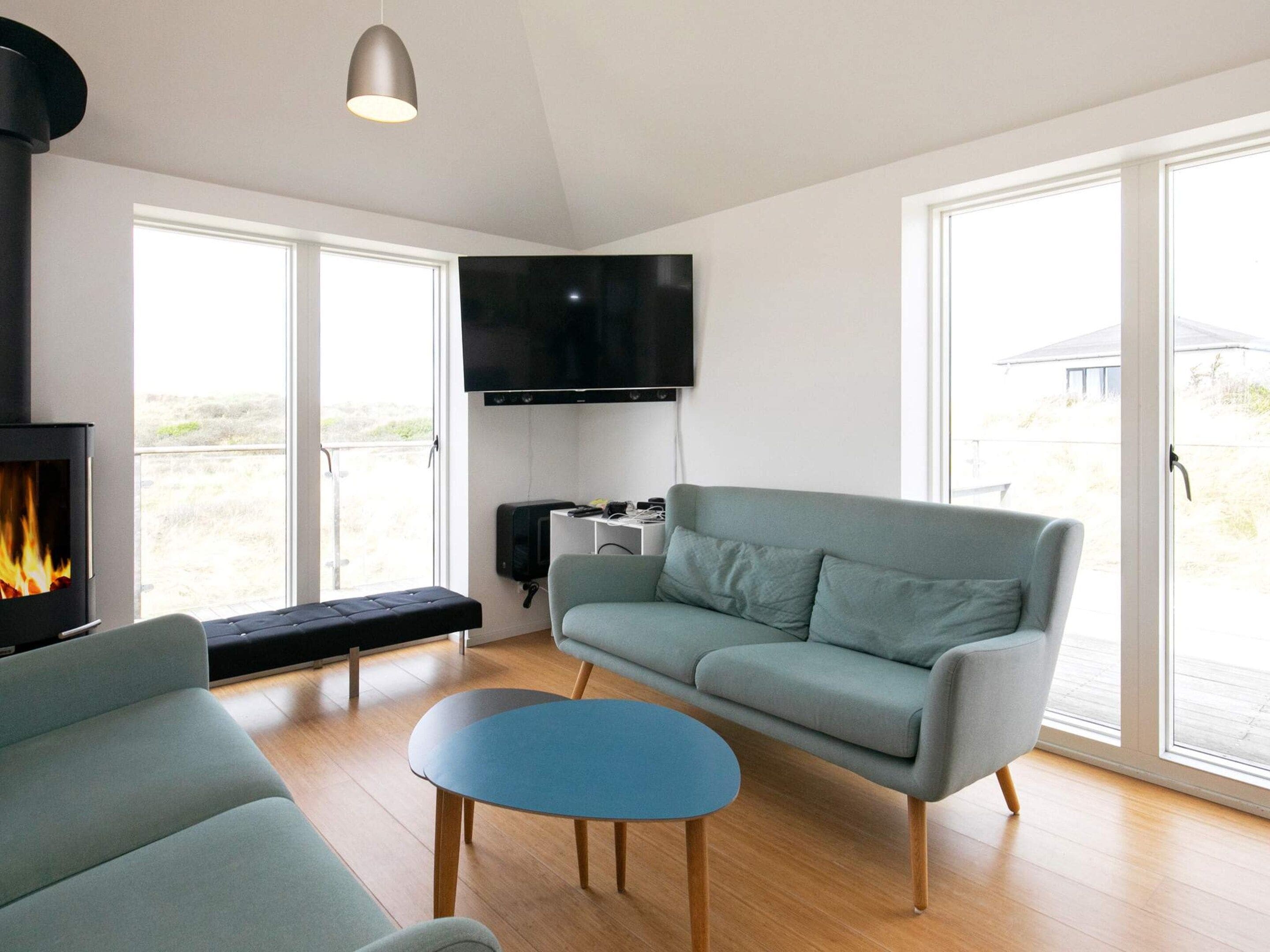 A modern living room with a sofa, a blue coffee table, a fireplace, and a TV mounted on the wall.