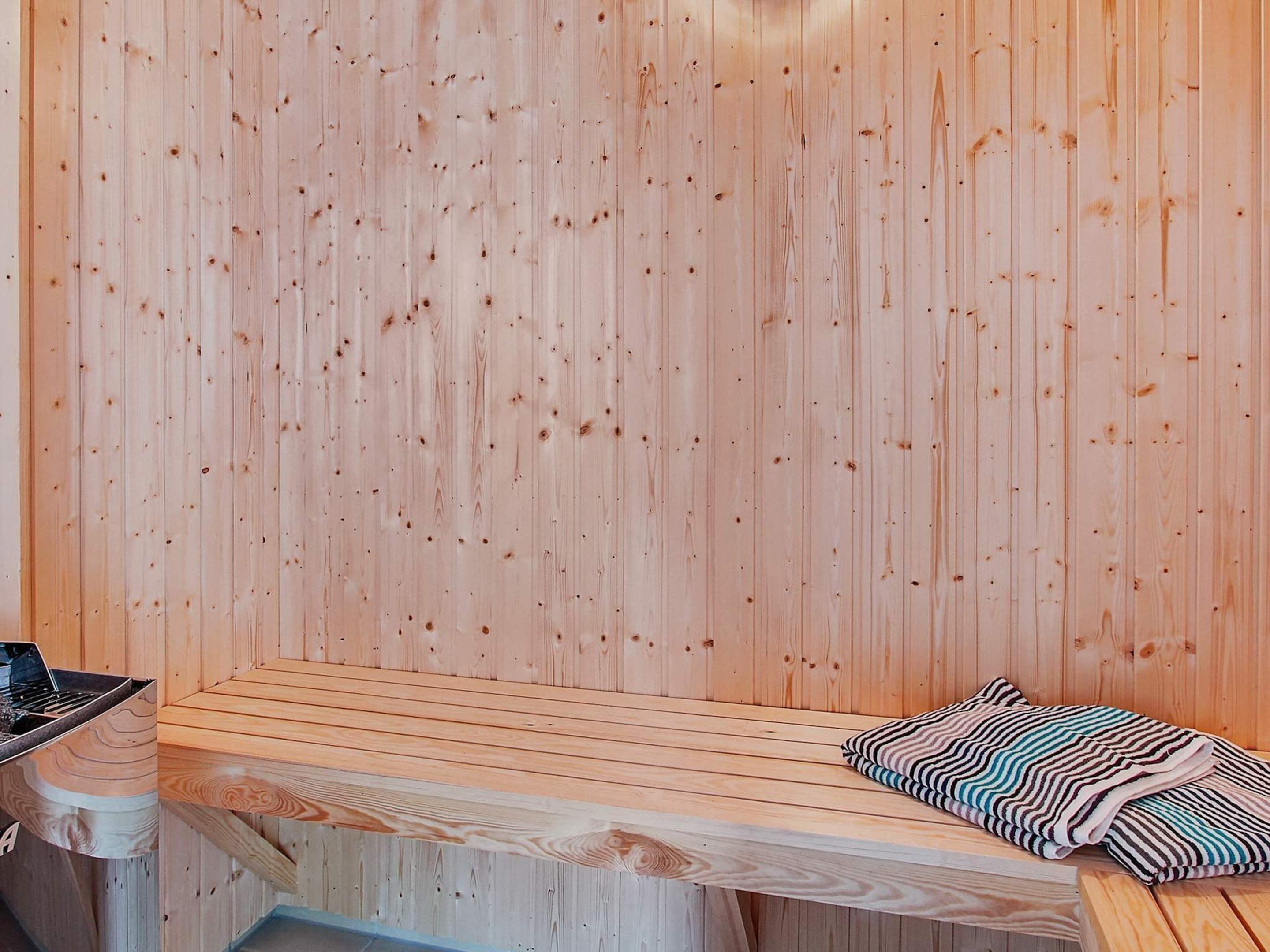 Un sauna avec un banc en bois et un banc recouvert d’une serviette à rayures.