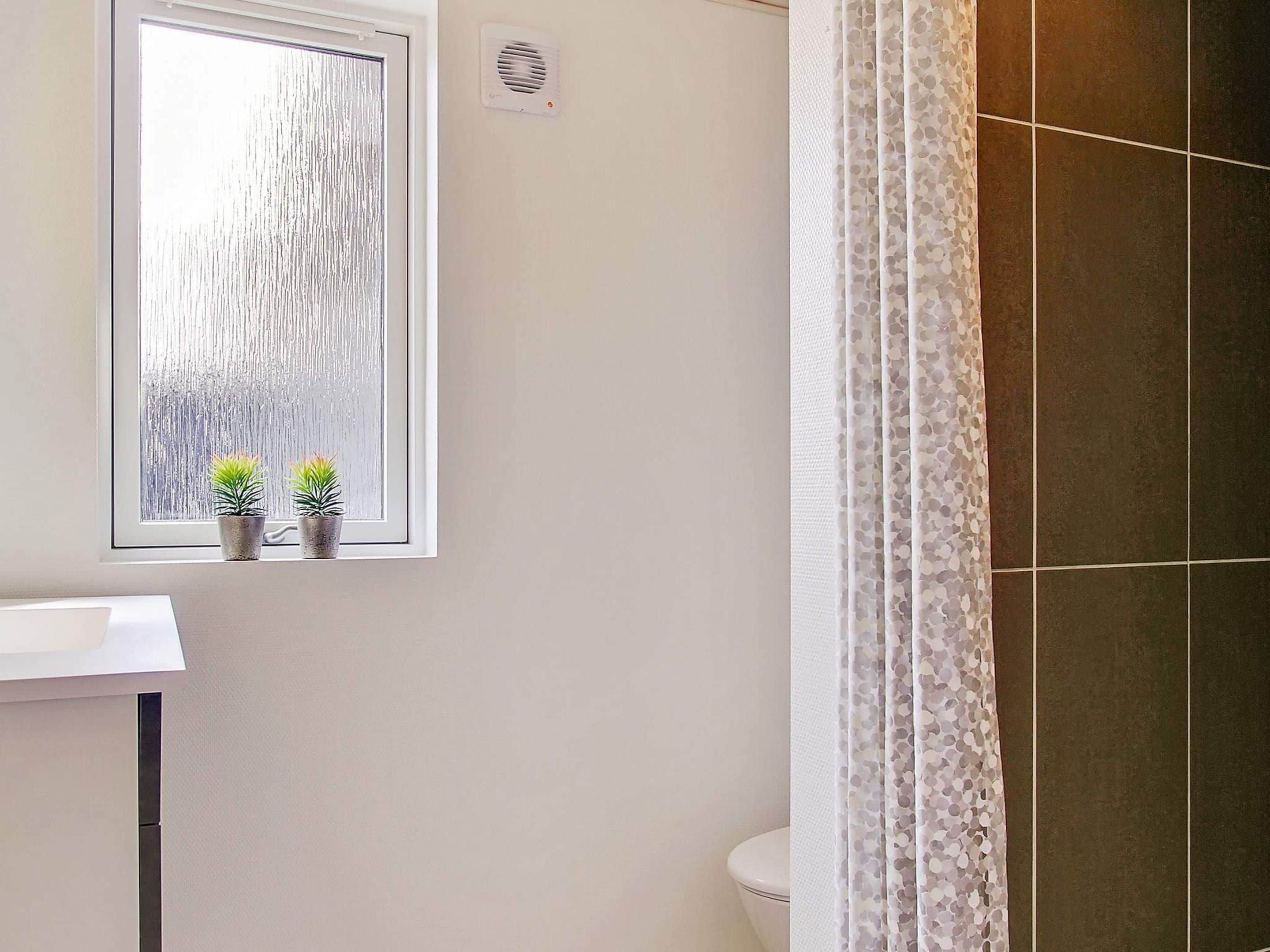 A bathroom with a window, a toilet, and a shower curtain.