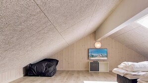 A room with a sloped ceiling, a bed, a television, and a small cabinet. - Holiday Home in Kappeln (Kappeln)
