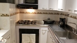 A compact kitchen with white cabinets, a gas stove, a built-in oven, a microwave, and a sink. - Nice Apartment 5 Minutes Airport (Bogotá)