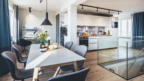 A modern kitchen with a dining area, featuring a large table, chairs, and a glass partition. - Beautiful apartment for 6 guests with pool, WIFI, TV, terrace and pets allowed (Sassnitz)
