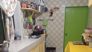Una cocina con estufa, armarios, una puerta verde y una mesa con mantel amarillo.