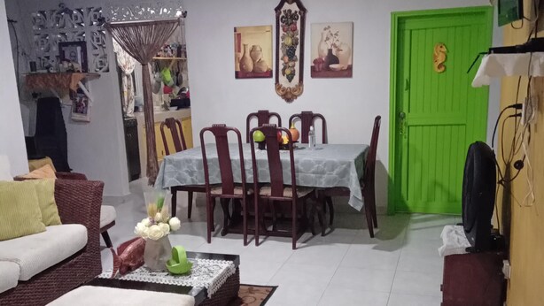Uma sala de estar com sofá, uma mesa de centro e um espaço de jantar com cadeiras e uma mesa.