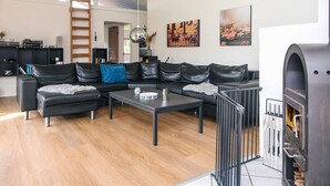 Een moderne woonkamer met een hoekbank, een salontafel en een open haard.