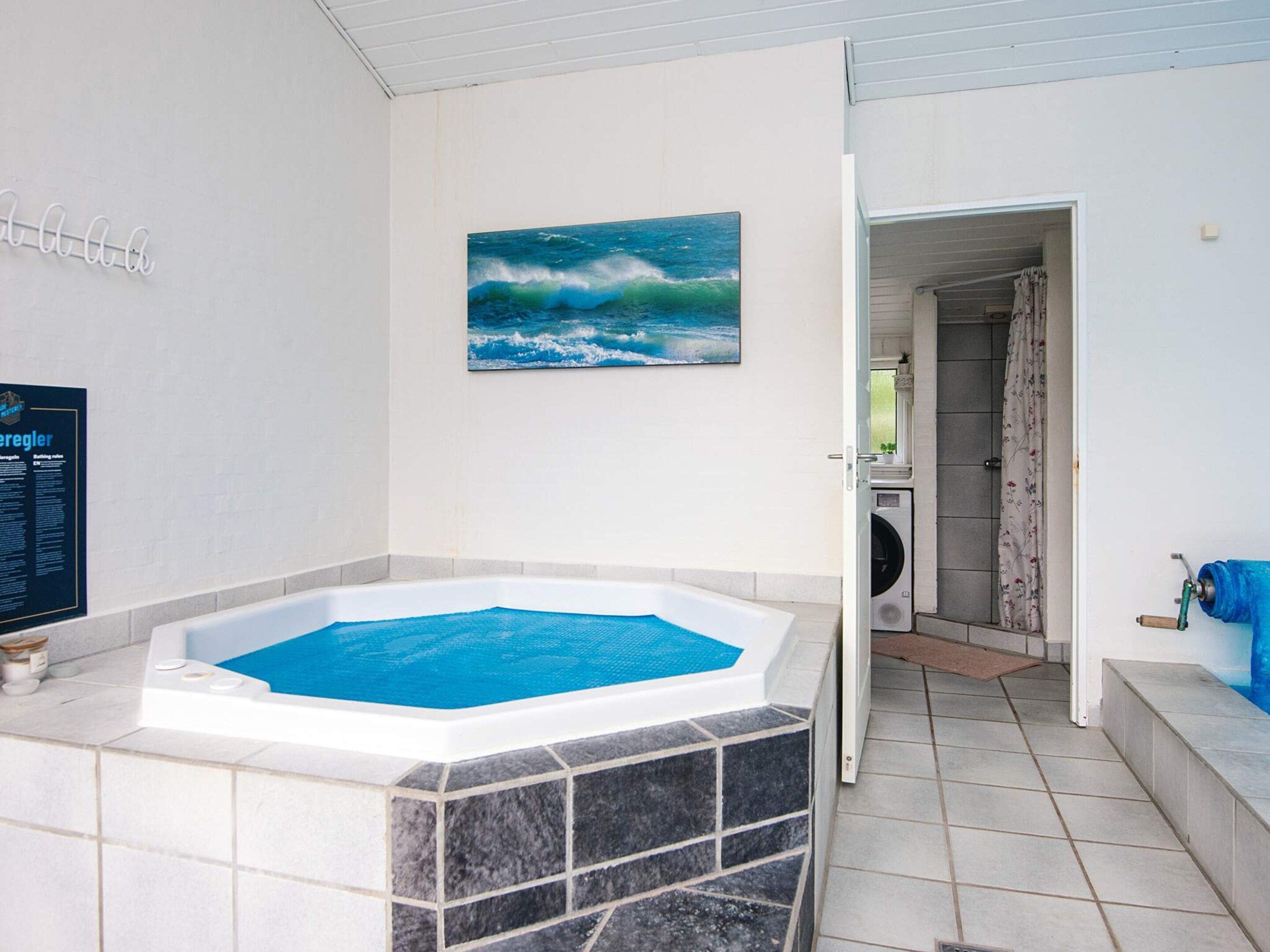 Un bagno con vasca, doccia e servizi igienici. Al muro, un quadro raffigura un'onda.