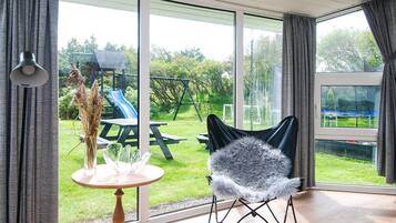A room with a large sliding glass door leading to a backyard with a slide and picnic table.
