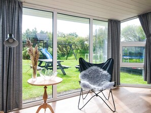 A room with a large sliding glass door leading to a backyard with a slide and picnic table.