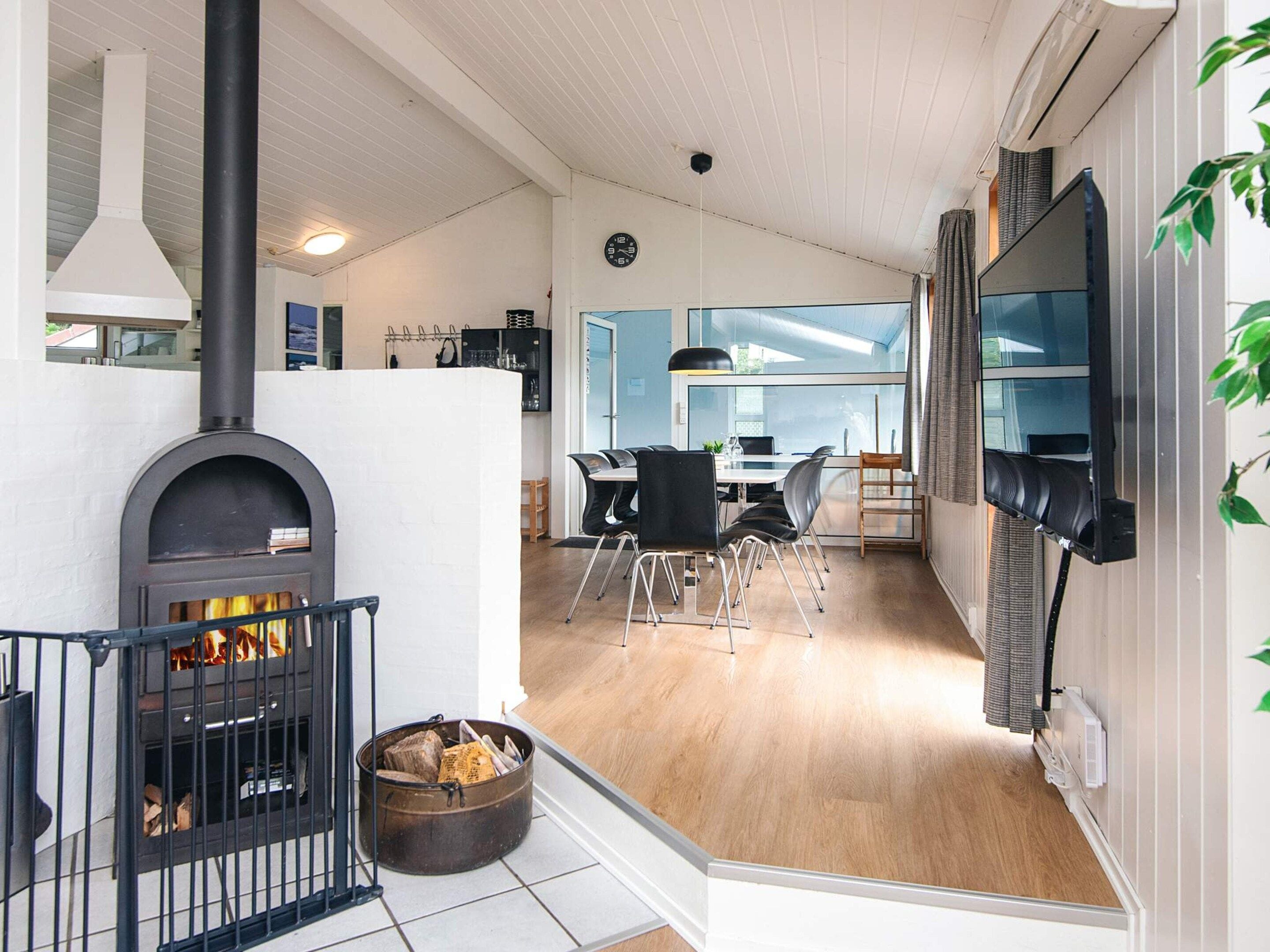 A modern interior with a fireplace, dining area, and a TV mounted on the wall.