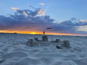 A sandy beach with a person standing near a structure made of concrete blocks. - 4 Star Holiday Home in Vejers Strand (Vejers Strand)