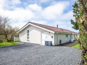 A single-story building with a tiled roof, a gravel driveway, and a white picket fence. - 4 Star Holiday Home in Vejers Strand (Vejers Strand)