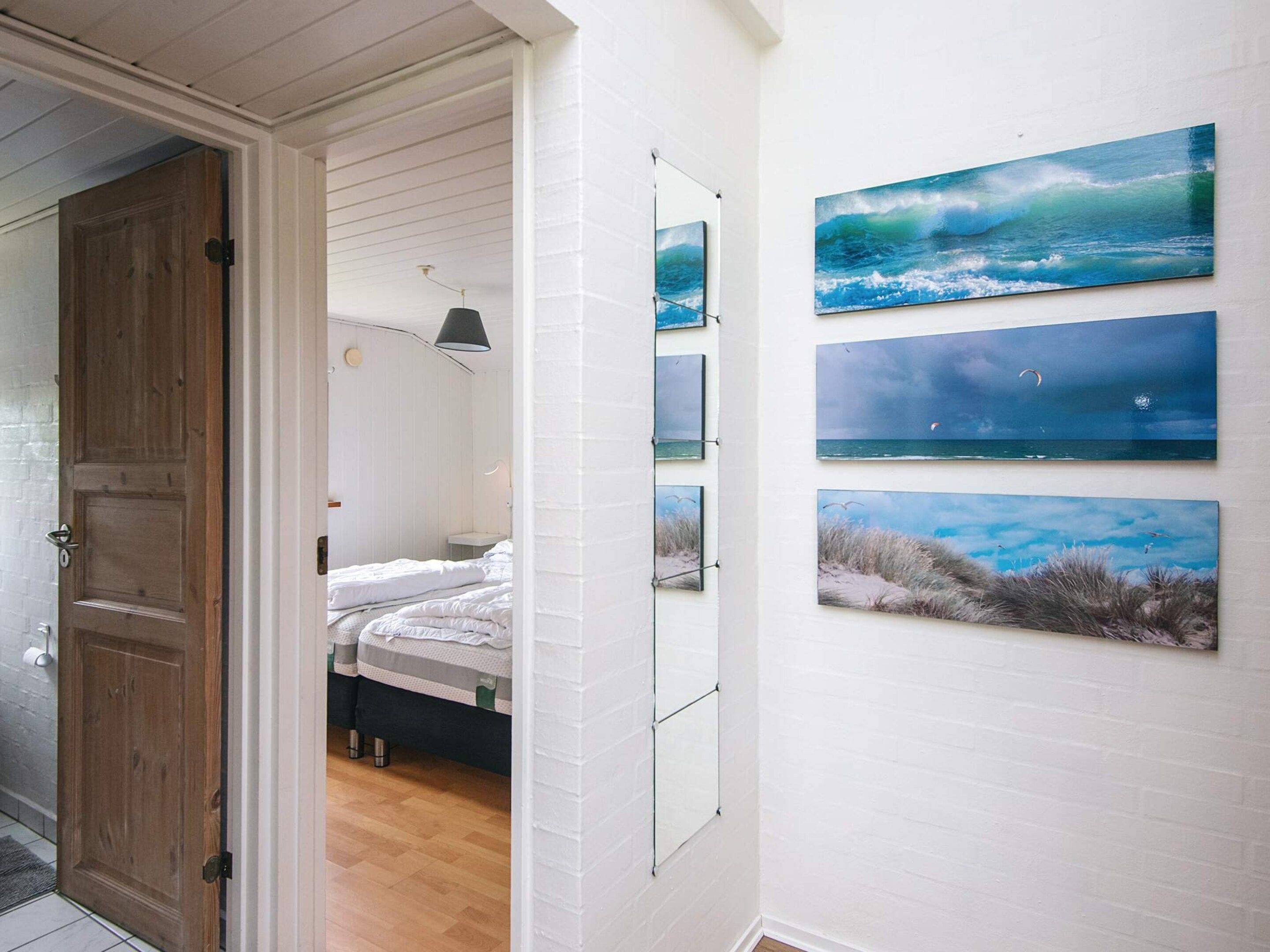A room with a bed, a door, and a wall with four framed pictures.