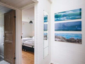 A room with a bed, a door, and a wall with four framed pictures.