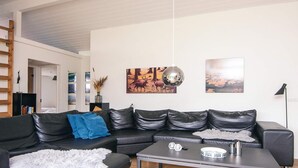Een moderne woonkamer met een hoekbank, een salontafel en kunstwerken aan de muren.