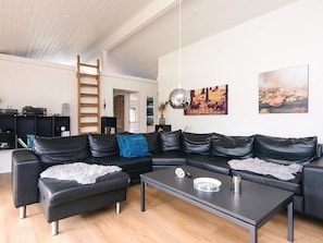 Ein modernes Wohnzimmer mit einem schwarzen Ledersofa, einem Couchtisch und einer Holzleiter.