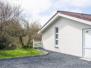 Un bâtiment à l’extérieur blanc, doté d’un toit recouvert de tuiles et d’une allée gravillonnée.