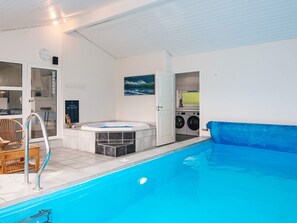 A swimming pool with a hot tub, a laundry area, and a seating area with a chair. - 4 Star Holiday Home in Vejers Strand (Vejers Strand)