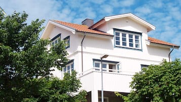 A two-story building with a white facade and red-tiled roof, surrounded by trees.
