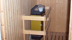 Un intérieur en bois avec un radiateur en métal et une étagère en bois sur laquelle se trouve un objet noir.