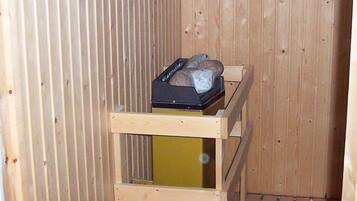 A wooden interior with a metal heater and a wooden shelf with a black object on it.