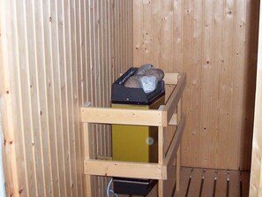 A wooden interior with a metal heater and a wooden shelf with a black object on it. - 2 Person Holiday Home in Kungshamn (Kungshamn)