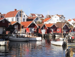 A harbor with boats docked and red-roofed buildings in the background.