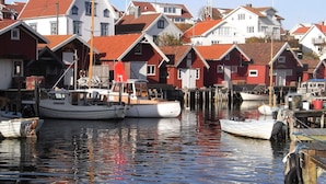 Un port où des bateaux sont amarrés, avec des bâtiments aux toits rouges en arrière-plan.