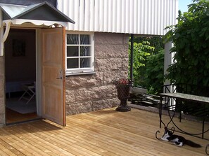 A wooden deck with a table and chairs, a cat, and a door leading to a room. - 2 Person Holiday Home in Kungshamn (Kungshamn)